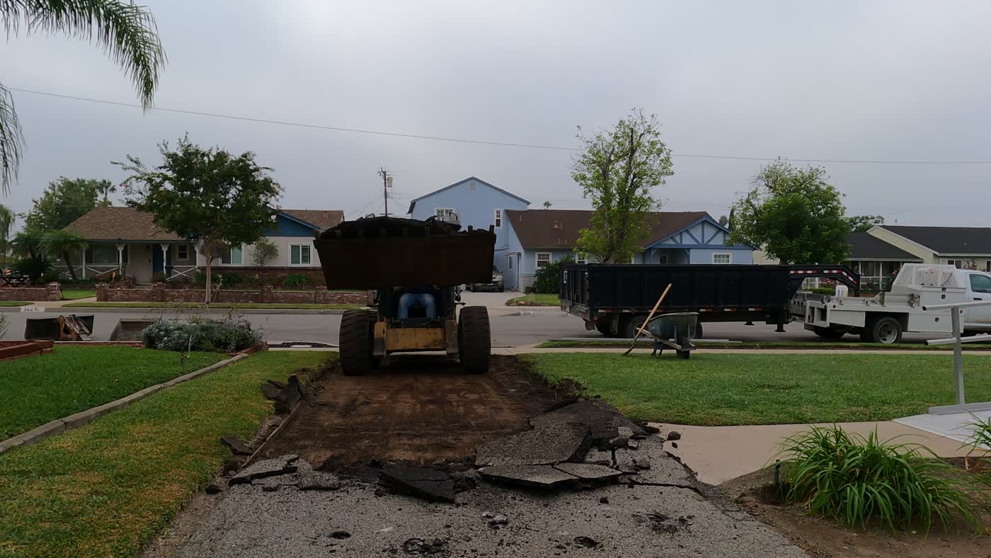 Skid steer breaking out the asphalt driveway