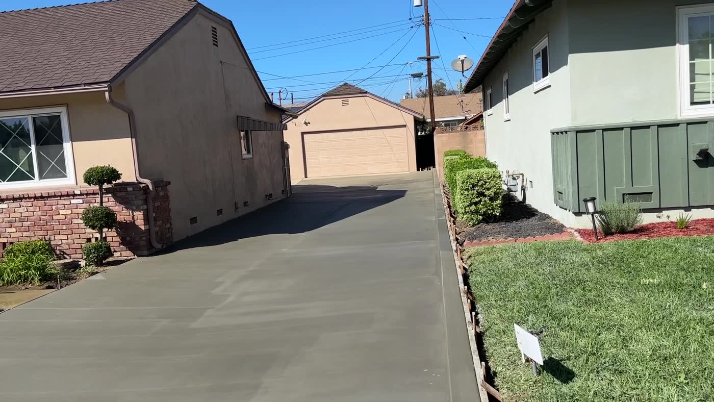 New concrete driveway running alongside the house to a detached garage in Covina
