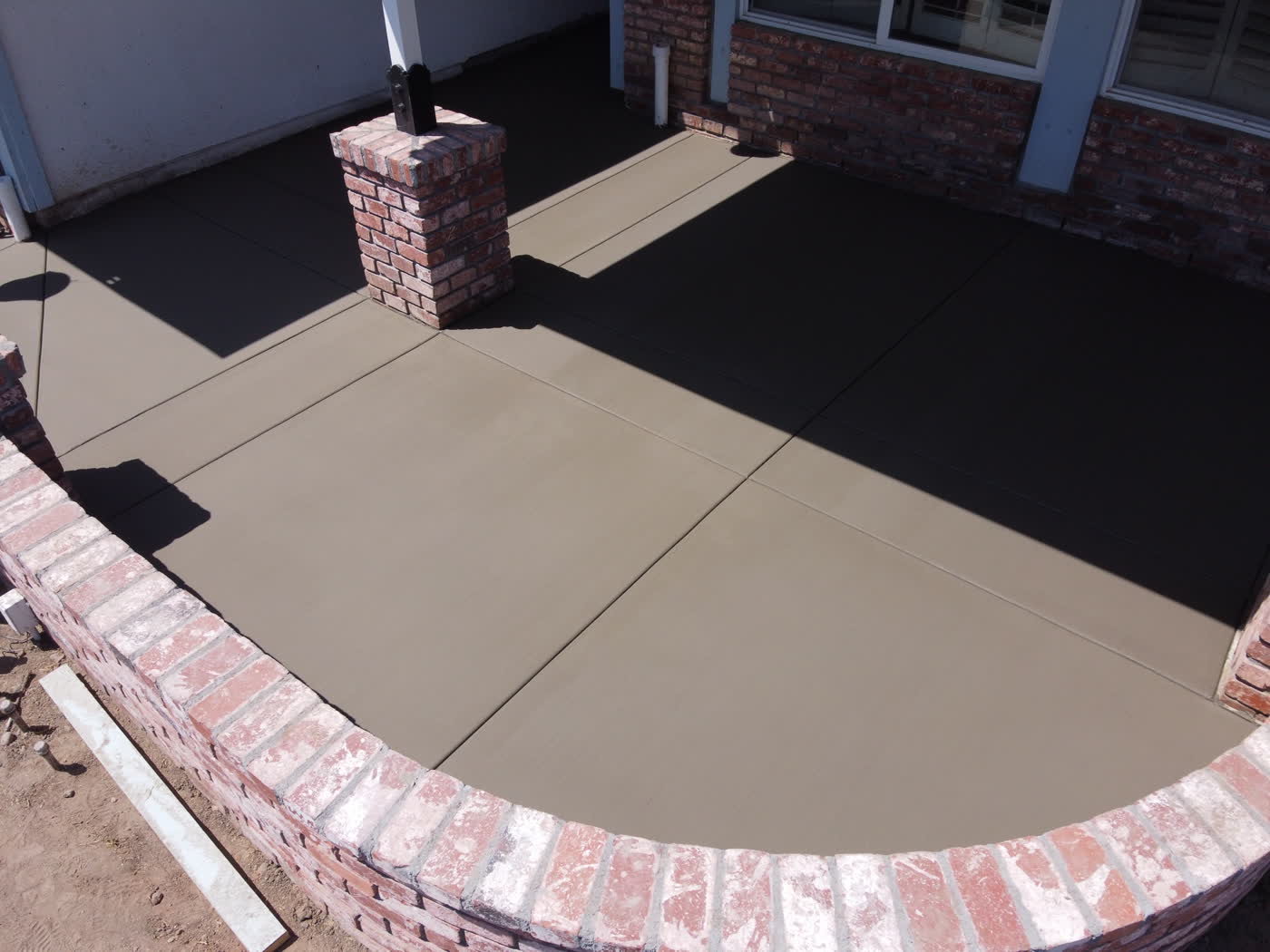 New entry slab framed by the curved brick planter wall