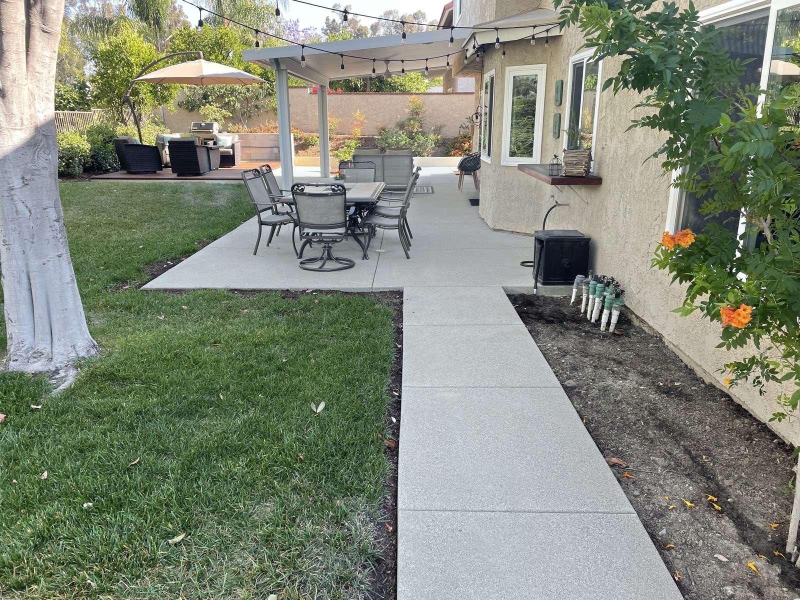 Concrete backyard patio and side walkway with a dining set